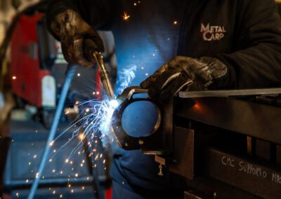 Operaio che esegue saldatura su un componente metallico, garantendo alta precisione e qualità nella lavorazione.