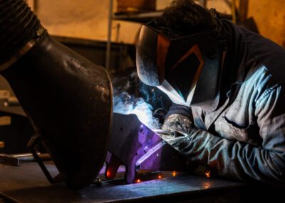 Operaio mentre esegue una saldatura su un componente metallico, garantendo precisione e qualità nel processo.