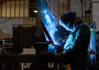 Componente metallico durante il processo di saldatura, con operaio che applica precisione e cura nella lavorazione.