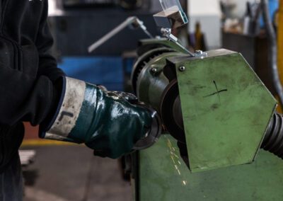 Operatore che utilizza un tornio per lavorare un componente metallico, assicurando precisione e qualità nella lavorazione.